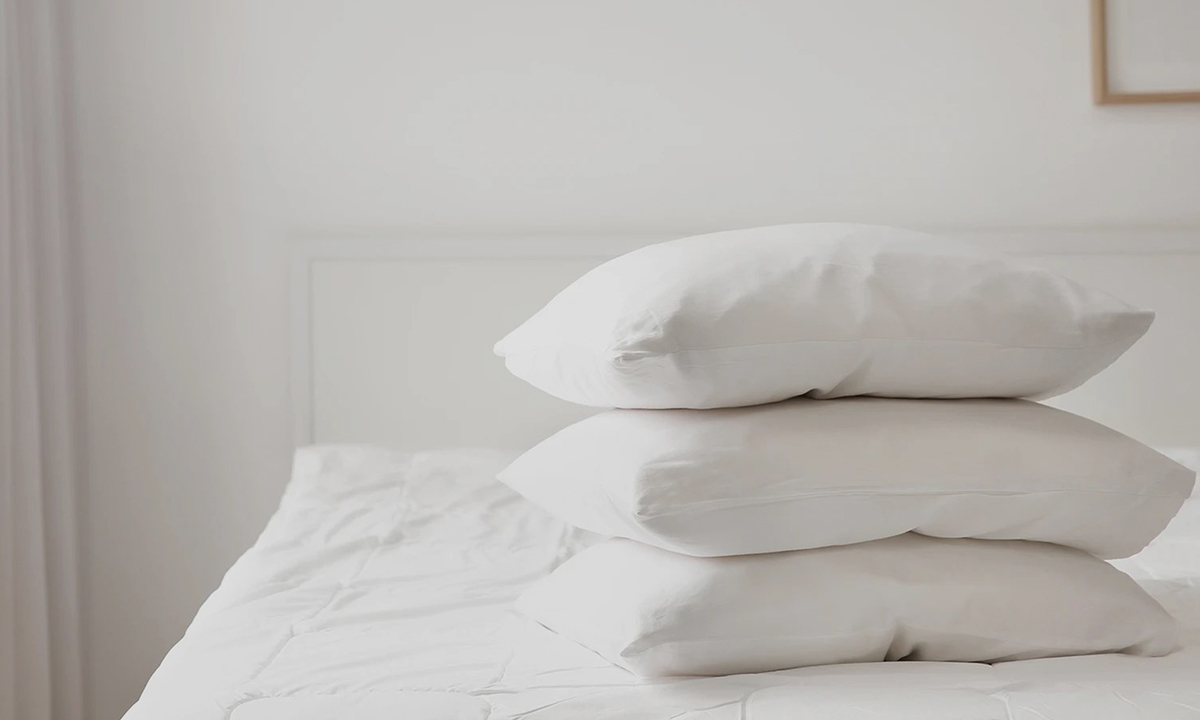 Giselle Bedding A bed with white sheets and three white Giselle Bedding pillows.